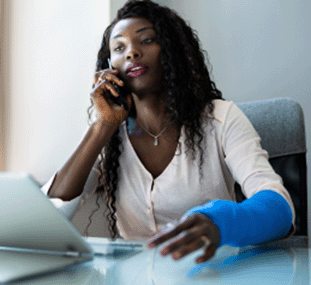 A woman with a cast on her hand and on the phone with a workers' comp agent