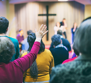 A couple of people raising their hands during worship