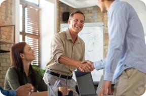 A photo of a human resources team with two men shaking hands in the forefront