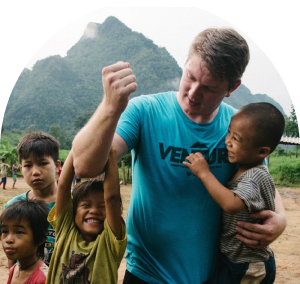 A man holding a child in his arm while playing with some other children on a mission trip